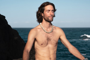 Mann macht Nackt-Yoga am Meer